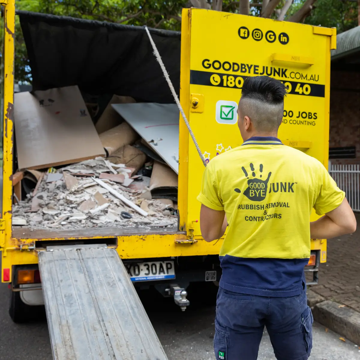Goodbye junk workerstanding next to their yellow rubbish removal truck
