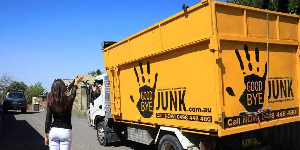 a woman standing next and waving bye to goodbye junk truck container